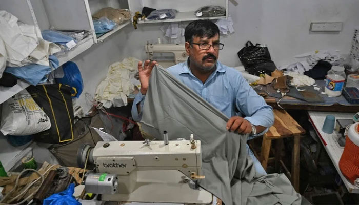 A tailor stitches a fabric at his shop in Islamabad on April 29, 2022. — AFP