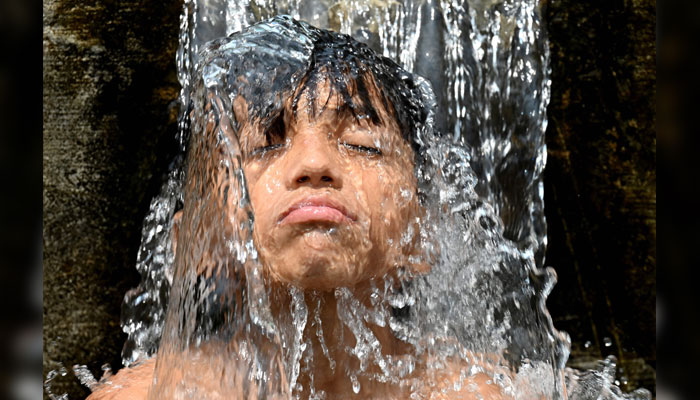 A boy showers under tube well water on a hot summer day in Lahore on May 20, 2025. — AFP