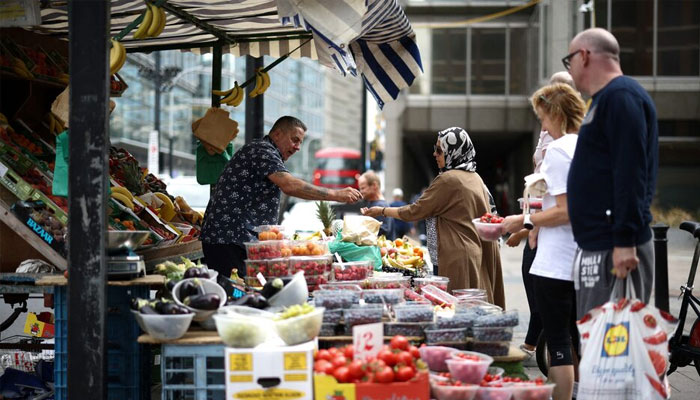 A person buys produce from a fruit and vegetable market stall in central London, Britain, August 19, 2022. — Reuters