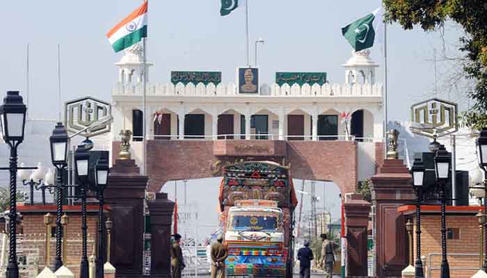 Indian and Pakistani national flags flutter as Indian Border Security Force (BSF) personnel (left) and Pakistani Rangers (right) allow a Pakistani truck to cross over to India at the Wagah Border India on February 24, 2010. — AFP