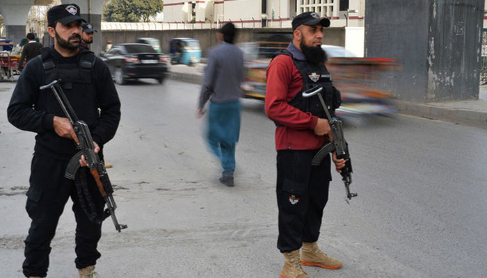 Policemen stand guard along a street in Peshawar. — AFP/File