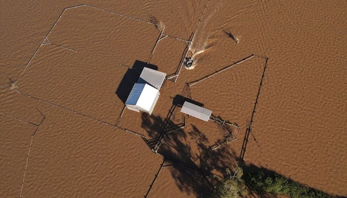 A drone view shows a boat approaching a flooded shed at a stud farm near the Hunter River in Heatherbrae, Australia, May 24, 2025.—Reuters