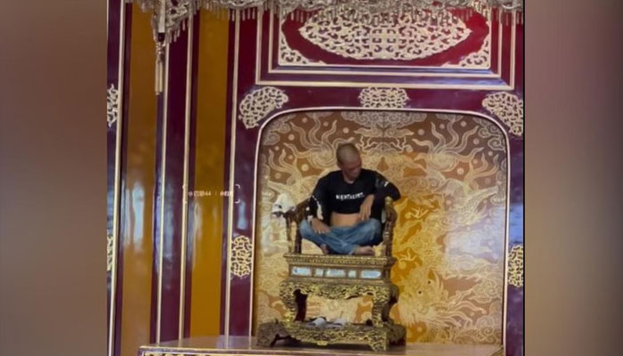 A man is seen sitting on a throne in footage circulating on social media and Vietnam news sites purportedly showing the Nguyen dynasty artefact incident in Vietnam.— Screengrab via Facebook