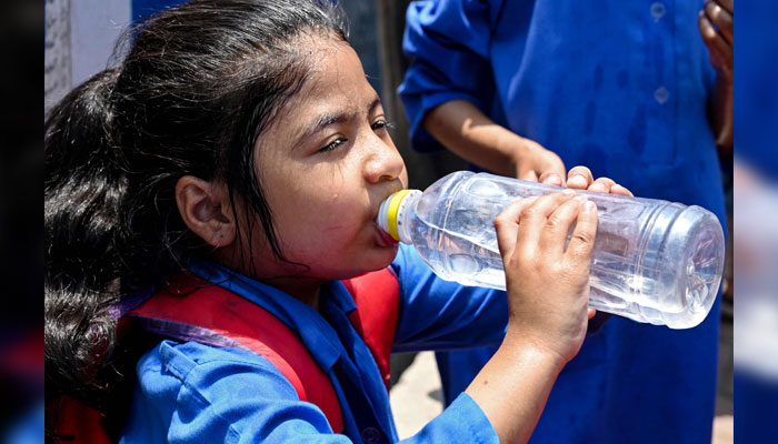 A schoolgirl drinks water at the end of her classes, on a hot summer day in Lahore on May 26, 2025. — AFP