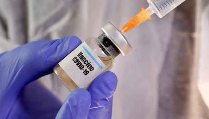 A woman holds a small bottle labelled with a Vaccine Covid-19 sticker and a medical syringe in this illustration taken April 10, 2020. — Reuters