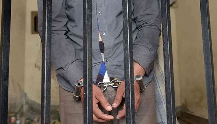 The picture shows a person handcuffed and standing behind bars. — AFP/File