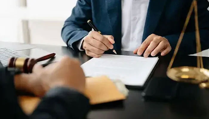 In this representational image, a lawyer writing on a paper at his chamber. — Unsplash/File