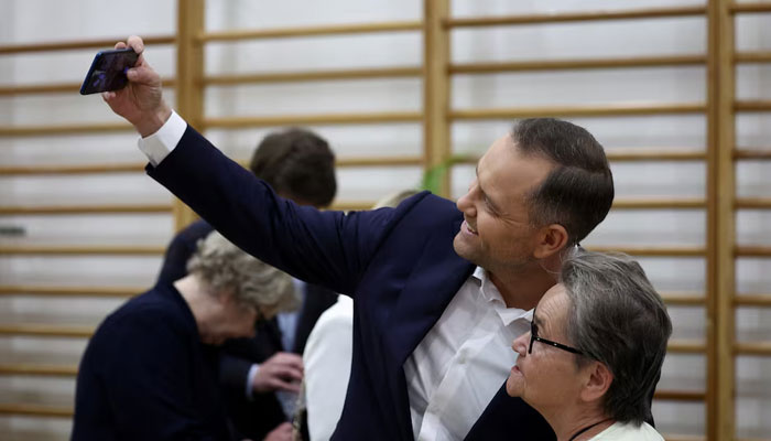 Polish presidential candidate Karol Nawrocki, backed by the main opposition Law and Justice (PiS) party, takes a selfie with a supporter, as he votes during the second round of presidential election, at a polling station in Warsaw, Poland, June 1, 2025.—Reuters