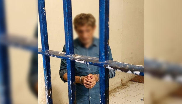 Prime suspect Salman Farooqi can be seen handcuffed and standing behind bars on June 2, 2025. — Facebook@KarachiPoliceOfficial
