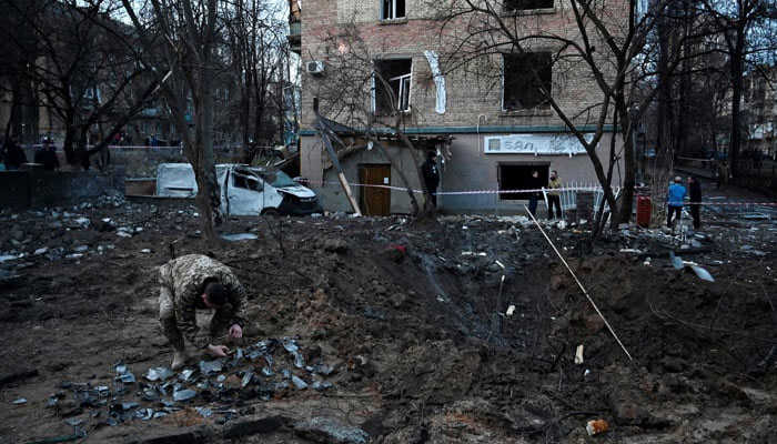 A serviceman collects fragments of missile in a crater left by a Russian strike. — AFP/File