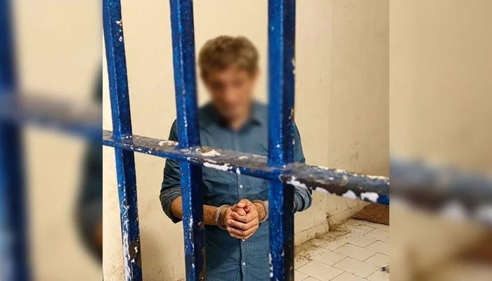 Prime suspect Salman Farooqi can be seen handcuffed and standing behind bars on June 2, 2025. — Facebook@KarachiPoliceOfficial
