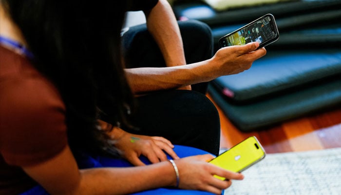 Two school students pose with their mobile showing social media applications in Melbourne, Australia, November 28, 2024. — Reuters