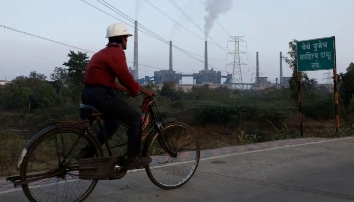 A factory worker rides a bicycle past the Super Thermal Power Plant in Chandrapur, India, February 3, 2025. — Reuters