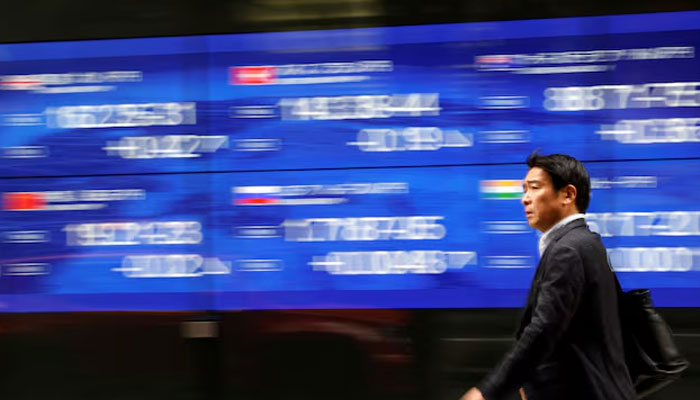 A passerby walks past an electric monitor displaying various countries stock price index outside a bank in Tokyo, Japan, March 22, 2023.—Reuters