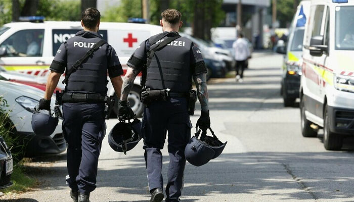 Two policemen walk past ambulance cars in a street close to a school where, according to reports, several people died in a shooting, on June 10, 2025 in Graz, southeastern Austria. — AFP