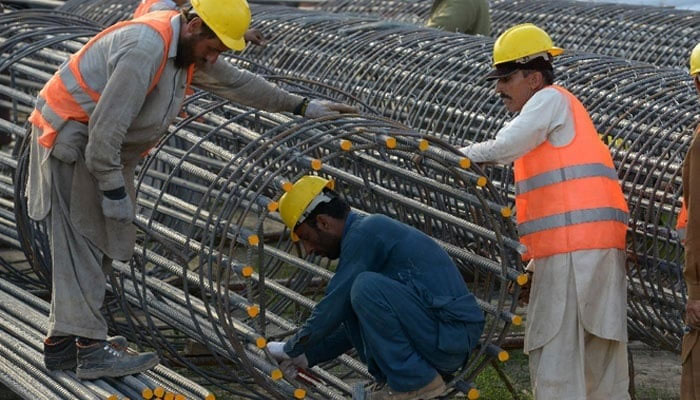 Labourers work at a construction site in Peshawar. — AFP/File