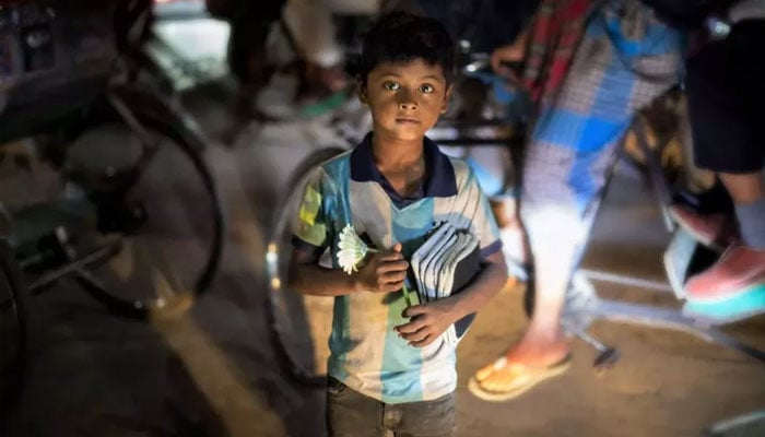 A child living and working in street situations sells flowers and household items for a living in the busy streets of Dhaka, Bangladesh on  February 16, 2023.—UNICEF