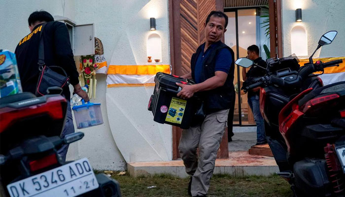 Plain-clothed police officers taking out evidences from villa. —AFP/File