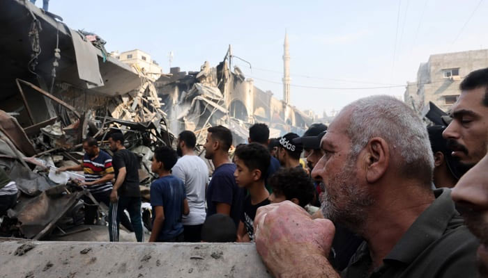 People watch as others sift through the rubble of a destroyed building following Israeli strikes on the Al-Shatee camp in Gaza City on October 28, 2023. — AFP