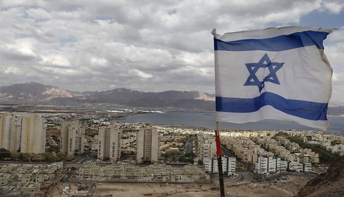 An Israeli flag flutters as the Red Sea resort city of Eilat and Jordans Red Sea resort city of Aqaba are seen in the background, on April 17, 2020. &mdash; AFP