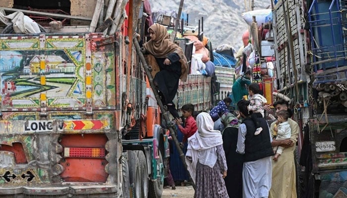 Afghan refugees climb a truck as they prepare to depart for Afghanistan, at a holding center in Landi Kotal, Pakistan, Nov. 1, 2023 — AFP