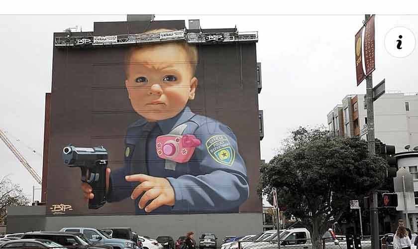 The baby police officer mural still looks out over the parking lot.