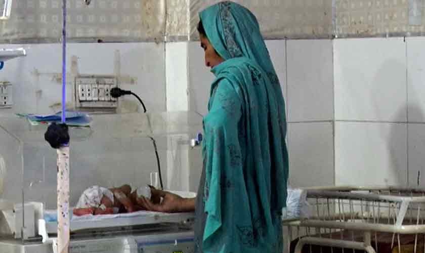 A grandmother stands next to an incubator looking at her grandson lying in an incubator at Lady Reading Hospital in Peshawar.