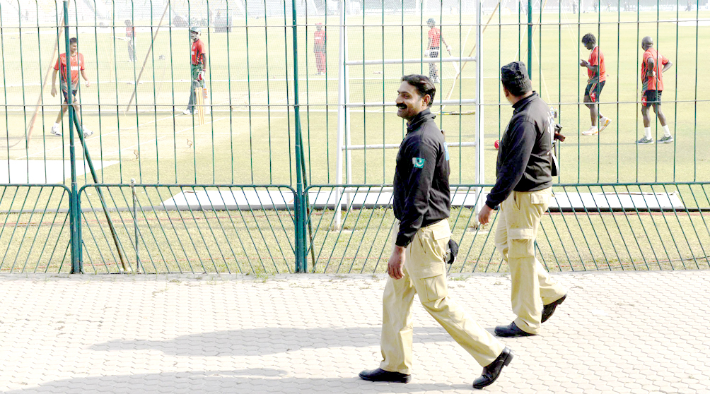 LAHORE: Policemen provide security as Kenyan cricket team members participate in a practice session at the Gaddafi Stadium here on Friday --AFP