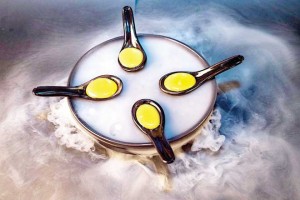 Chilled mango juice in soup spoons, fixated into its spherical shape by liquid nitrogen. 