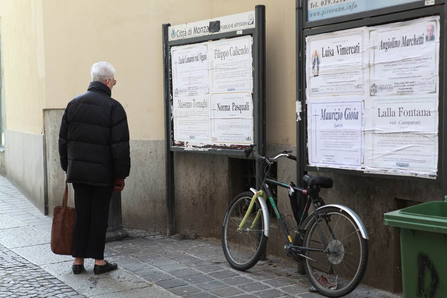 A woman looks at one of the many obituary boards across town