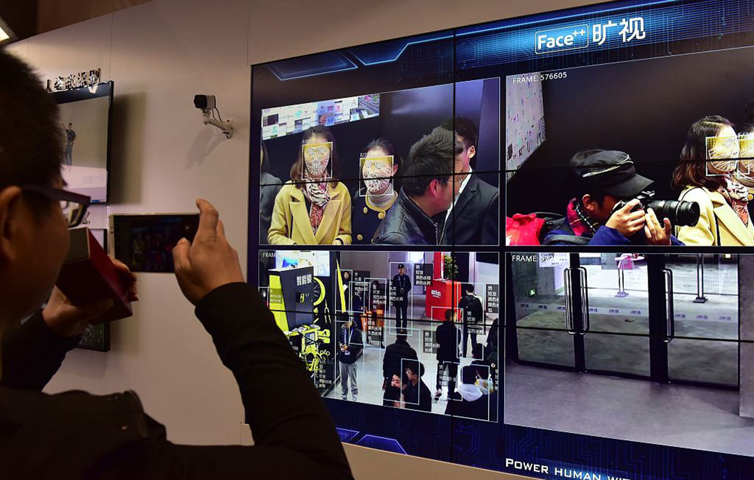 A visitor snaps a photo of video demonstrating a city surveillance system that features facial recognition technology.