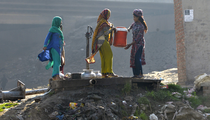 Photo of women filling water in large containers in the outskirts of Lahore — AFP.