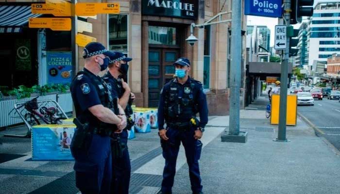 Personnel of Australian police stand outside a shop.