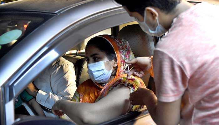 A woman being injected COVID-19 vaccine at a drive-through vaccination center setup at the Gaddafi Stadium in Lahore. Photo: APP