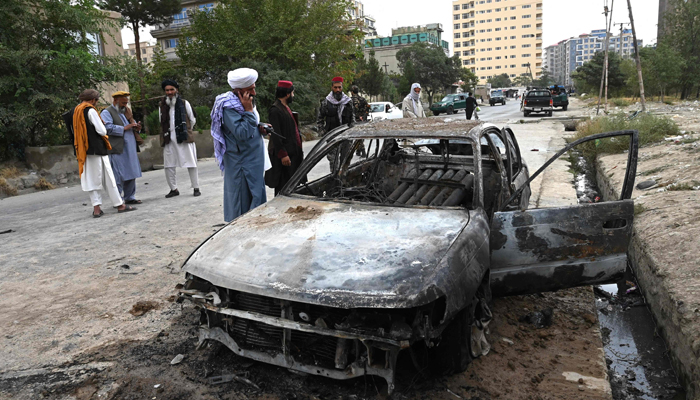 Taliban fighters investigate a damaged car after multiple rockets were fired in Kabul on August 30, 2021. Rockets flew across the Afghan capital on August 30 as the US raced to complete its withdrawal from Afghanistan, with the evacuation of civilians all but over and terror attack fears high. — AFP