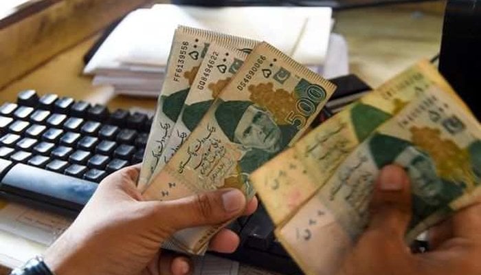 A currency exchange trader counts money at his office in Islamabad. — AFP/File