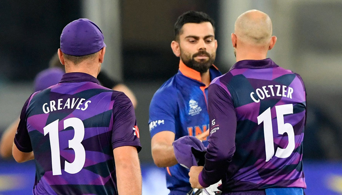 India´s captain Virat Kohli (C) shakes hands with his Scotland´s counterpart Kyle Coetzer (R) as Chris Greaves watches at the end of the ICC Twenty20 World Cup cricket match between India and Scotland at the Dubai International Cricket Stadium in Dubai on November 5, 2021. — AFP