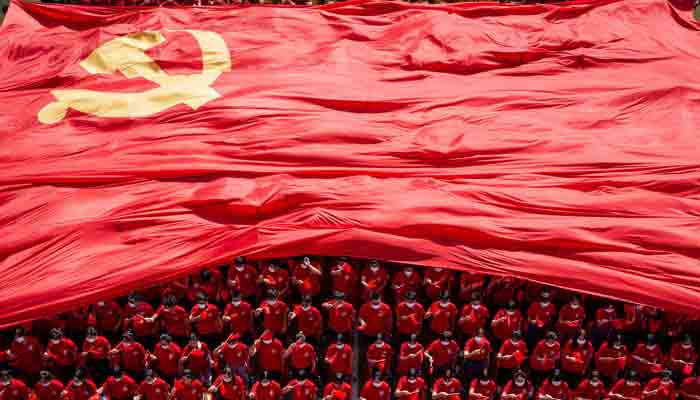 This file photo taken on September 10, 2021, shows university students displaying the flag of the Communist Party of China to mark the party´s 100th anniversary during an opening ceremony of the new semester in Wuhan in China´s central Hubei.-AFP