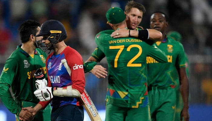 England´s Mark Wood (2L) walks past South African players celebrating their win in the ICC Twenty20 World Cup cricket match between England and South Africa at the Sharjah Cricket Stadium in Sharjah on November 6, 2021. — AFP