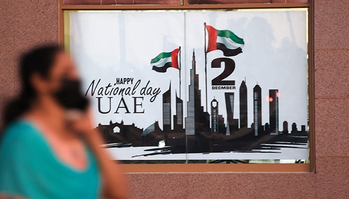 A woman walks past a poster celebrating the upcoming United Arab Emirates 50th anniversary which falls on December 2, in the Gulf emirate if Dubai, on November 29, 2021. — AFP/File