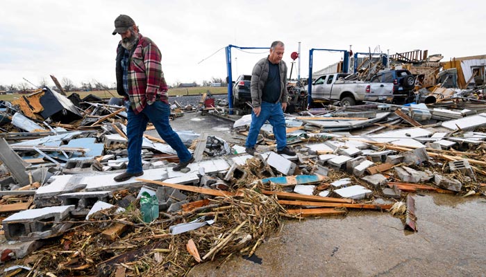 Martin Bolton (L) and shop owner Danny Wagner look through the debris of Wagner´s automobile repair shop after it was destroyed by a tornado in Mayfield, Kentucky, on December 11, 2021. — AFP