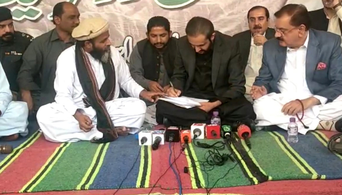Chief Minister Balochistan Mir Abdul Qudoos Bizenjo (C) signing a deal, with Balochistan general secretary of Jamaat-e-Islami, and the leader of the ‘Gwa­dar ko haq do’ movement, Maulana Hidayatur Rehman looking on, in Gwadar, Balochistan. — Twitter