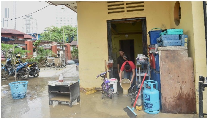 People clean up their house after it was hit by a flood in Kuala Lumpur Malaysia on December 19, 2021. — Arif Kartono / AFP