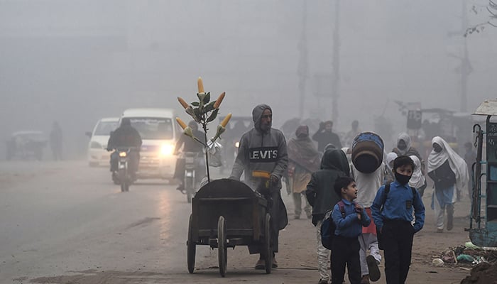 Children walk to school amid smoggy conditions in Lahore on December 16, 2021. — AFP