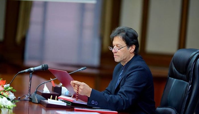 Prime Minister Imran Khan reading a document in this PID file photo.