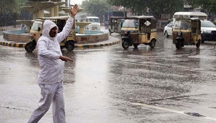 A traffic cop regulates traffic amid heavy downpour. Photo: Geo.tv/file