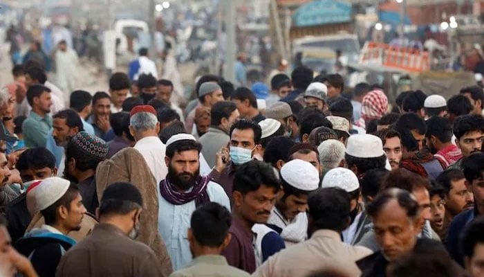 ماسک پہنے ایک شخص عارضی بازار کے ساتھ لوگوں کے ہجوم میں سے گزر رہا ہے کیونکہ کراچی میں کورونا وائرس کا پھیلاؤ جاری ہے۔  تصویر: فائل