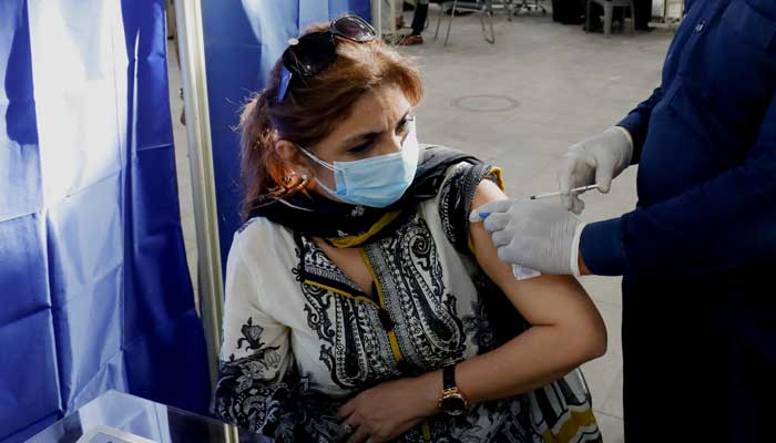 صحت کی دیکھ بھال کرنے والا کارکن ایک خاتون کو COVID-19 ویکسین لگا رہا ہے۔  -اے پی پی