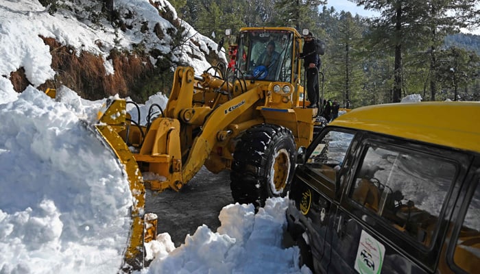 Pekerja menggunakan alat berat untuk membersihkan jalan setelah badai salju yang dimulai pada 7 Januari menjebak pengunjung di kendaraan di sepanjang jalan menuju kota resor bukit Murree, sekitar 70 km timur laut Islamabad pada 9 Januari 2022. — AFP