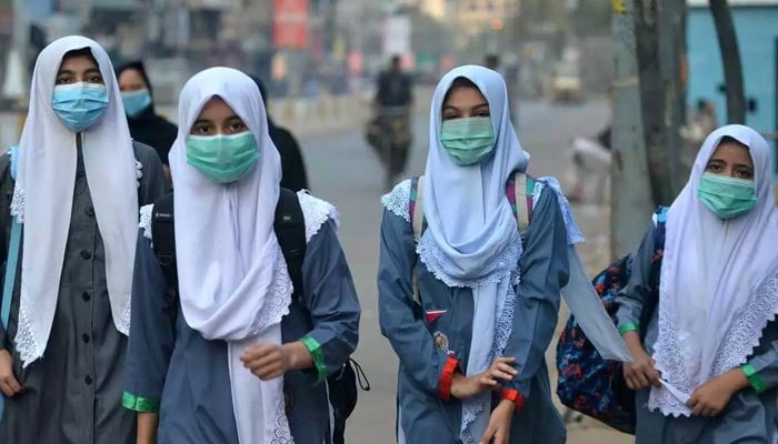 Siswa yang memakai masker sedang dalam perjalanan ke sekolah di Karachi.  — AFP/File